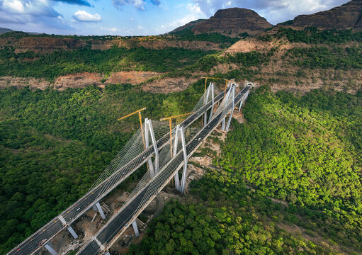 Aerial view of the Mumbai-Pune Expressway Missing Link Project cable-stayed bridge under construction, featuring tall pylons and cranes in Khopoli, Maharashtra, India.