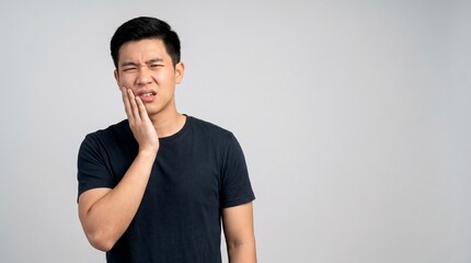 Obraz premium Young Asian Man Suffering from Severe Toothache and Touching His Cheek with Copy Space