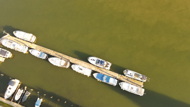 Aerial view of various motorboats and yachts moored along a wooden pier in the river in Chartrettes, Ile-de-France, France.