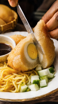 Close up of boiled egg being sliced over pempek, noodles, cucumber, and dark sauce .generative AI