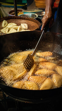 Pempek fish cakes frying in hot oil inside a dark wok at a traditional kitchen stall .generative AI