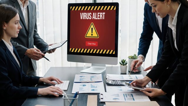 Business team looking at computer screen with virus alert warning in modern office