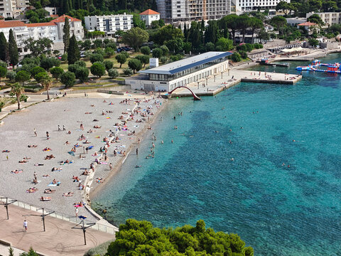 Lively crowd relaxing on Lapad Beach in Dubrovnik, capturing the essence of sunny Mediterranean summer vacation