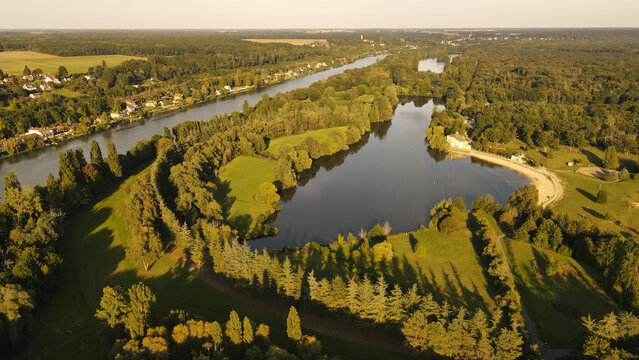 Aerial view of the Seine river winding through the lush green landscape and forests of Chartrettes, Ile-de-France, France.