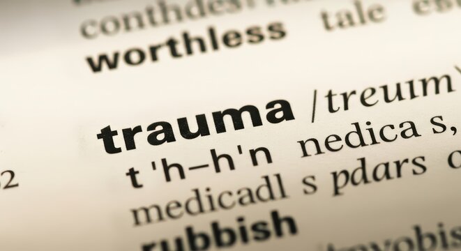 Close-up of the Word Trauma in a Dictionary Definition with Worthless and Rubbish in Background for Mental Health Concept