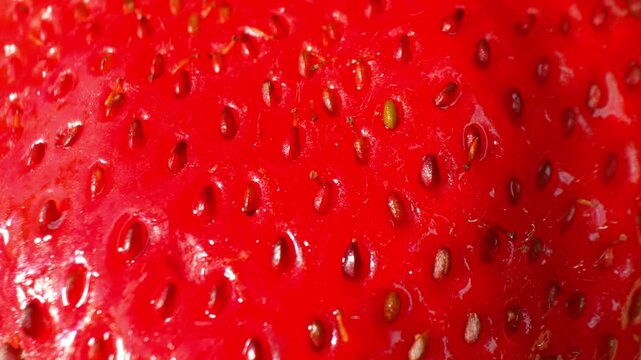 Bright red strawberry macro background with visible seeds and smooth surface, symbolizing vitality, natural beauty, growth, abundance, and the richness of nature. 4k.
