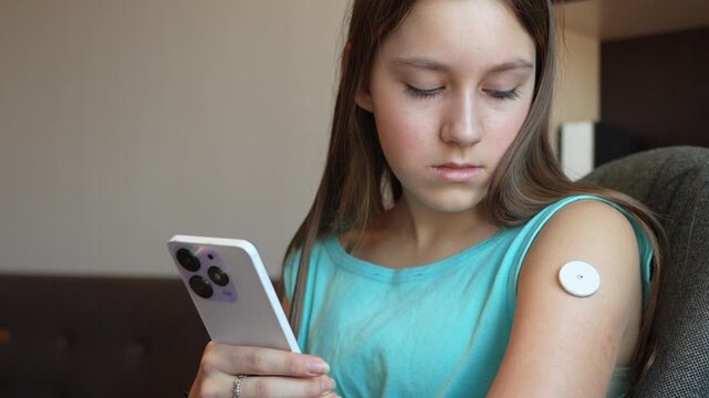 Caucasian Girl with diabetes checking blood glucose level at home using continuous glucose monitor. girl checks the glucose level