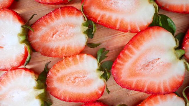 A collection of strawberry halves creates a colorful food background, representing freshness, culinary preparation, fruit consumption, and healthy lifestyle choices. 4k.
