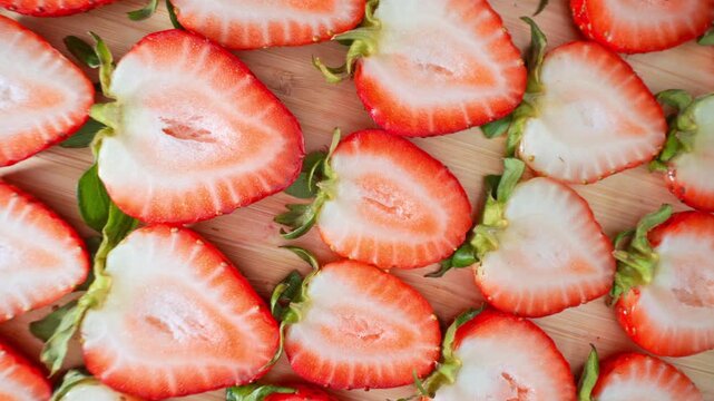 Fresh strawberry halves arranged on a wooden surface reveal their juicy interiors and delicate textures, highlighting healthy nutrition, natural sweetness, fresh produce and premium fruit quality. 4k.
