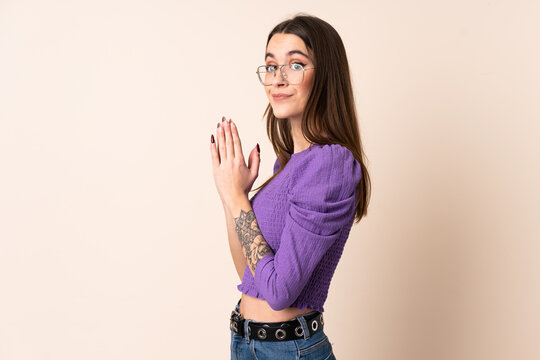 Young woman over isolated beige background scheming something