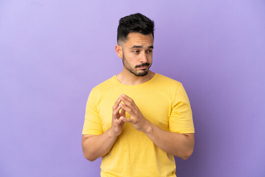 Young caucasian man isolated on purple background scheming something