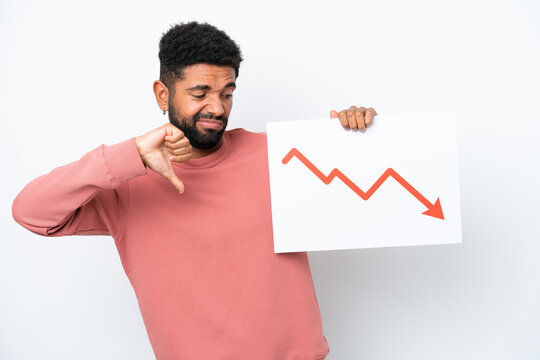 Young Brazilian man isolated on white background holding a sign with a decreasing statistics arrow symbol and doing bad signal