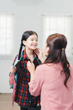 A mother helping her young daughter get ready for school at home in the morning