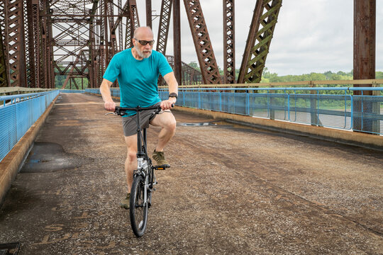 senior athletic man with a folding bike - biking on a historic Chain of Rock Bridge over Mississippi River above St Louis