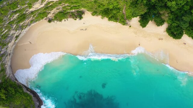 Aerial top down view of big ocean waves crashing on a sandy beach. Nature background with sea surf foam for summer vacation and travel concepts.