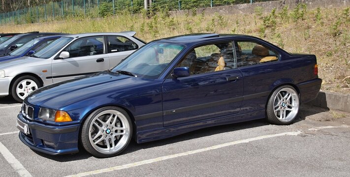 Dark blue BMW E36 coupe parked on tarmac
