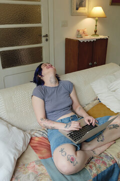 Young adult having fun browsing their laptop in their home