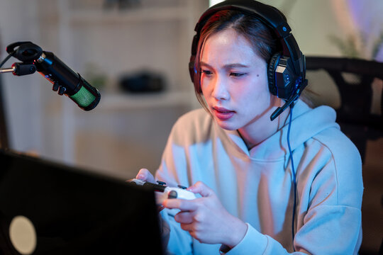 Focused streamer playing video games live professional headset microphone controller in home gaming studio