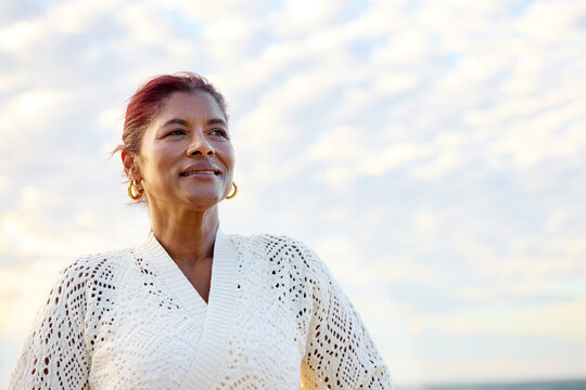 Woman Standing Under Clouds at Sunset