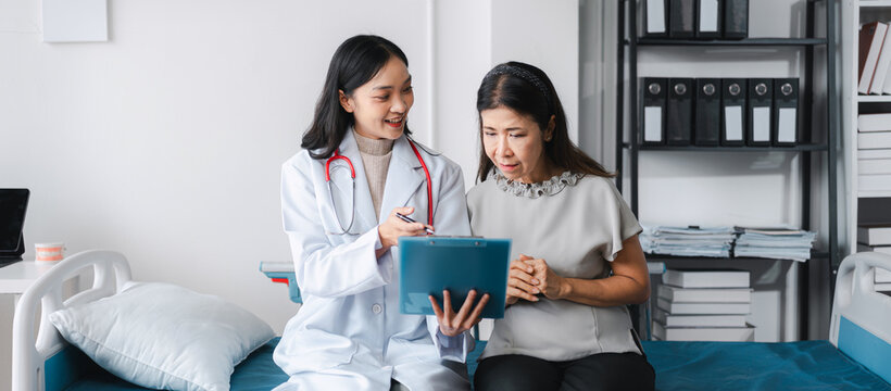 Asian Young Doctor Explains Diagnosis to Older Patient in Clinic