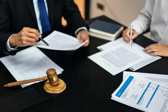 Two men are sitting at a table with papers and pens