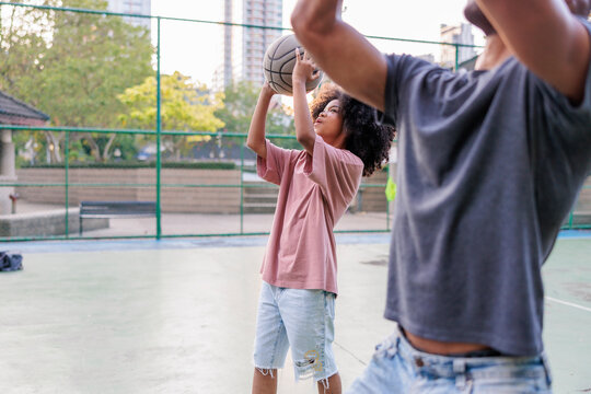 Two people playing basketball on an outdoor court.