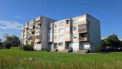 Modernist multi story apartment block with balconies and green lawn under blue sky © hecos