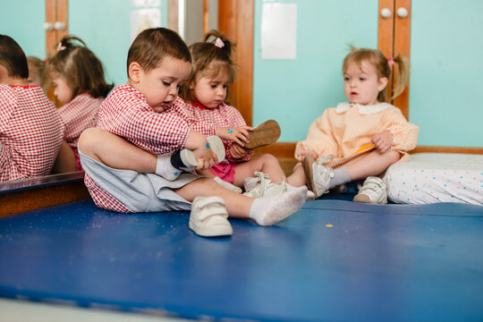 Kindergarten children learning independence putting on shoes