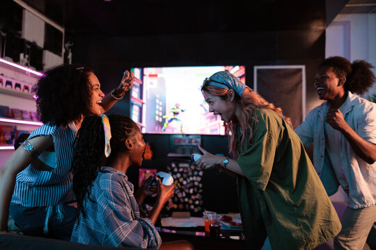 Friends excitedly playing video games together in a gaming lounge.