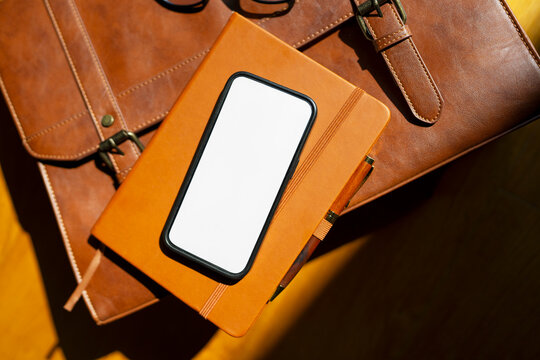 Smartphone on a brown notebook and bag
