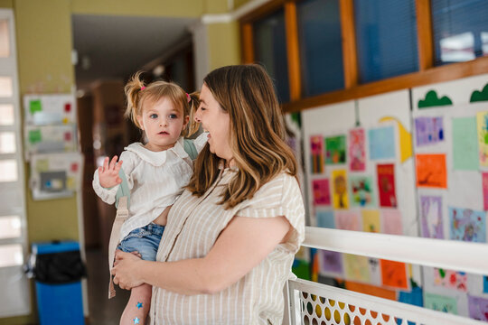 Mother holding child smiling at daycare or preschool