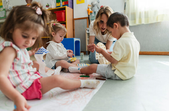 Teacher helping children learning and playing in kindergarten