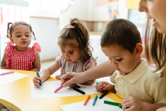 Young children drawing with crayons in preschool classroom