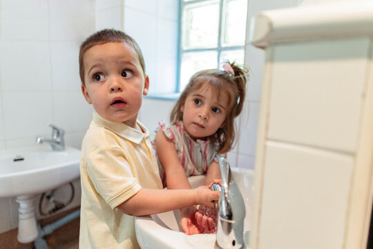 Children washing hands learning hygiene in bathroom