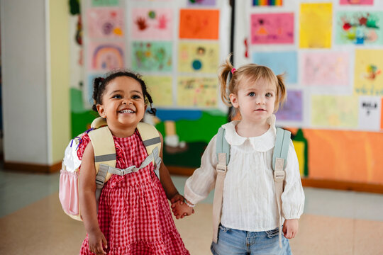 Diverse little girls holding hands going to kindergarten