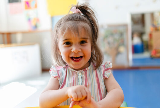 Happy toddler girl smiling at kindergarten classroom