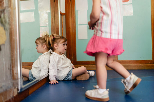Little girl watching reflection in mirror at kindergarten