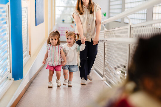 Teacher walking two preschool girls in school hallway
