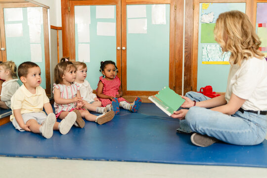 Teacher reading story to diverse group of preschool children