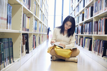 Young female student reading in library aisle © KieuLan