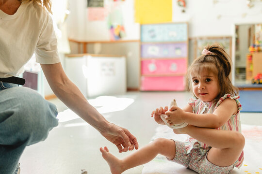 Young girl putting on sock with adult help