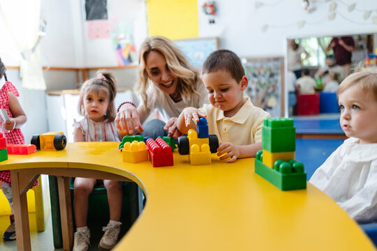 Teacher assisting young children playing with building blocks