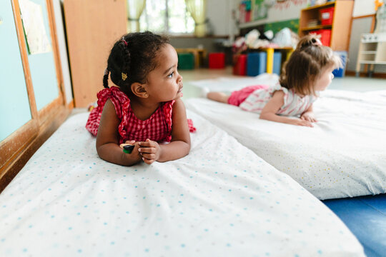 Diverse toddlers resting on mats in daycare classroom