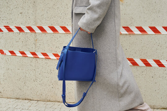 Person walks with blue bag next to caution tape