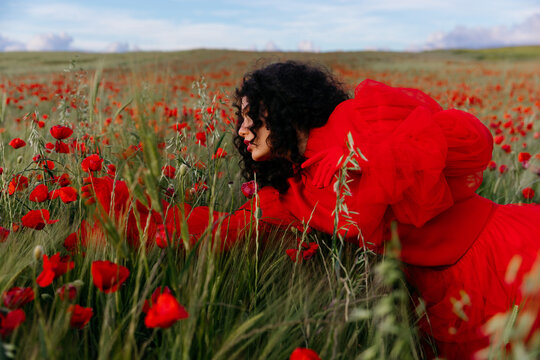 Woman in red dress among red poppies