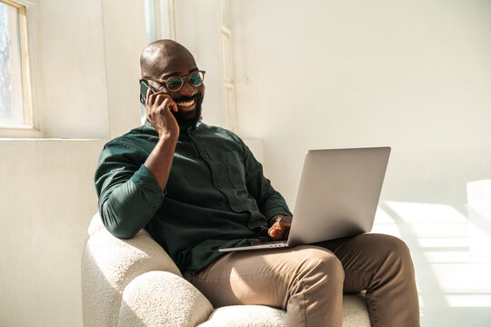 Happy Professional Man Working on Laptop While Talking on Phone
