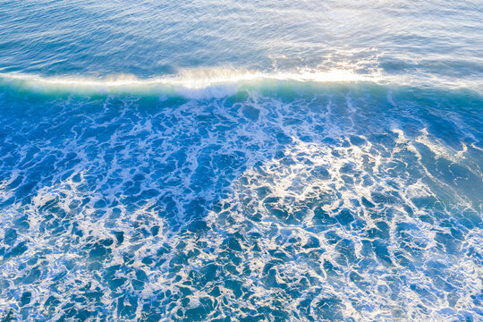 Sunlit waves rolling onto beach