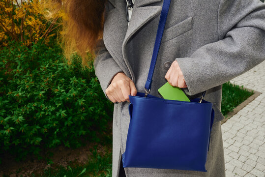 Woman takes a card from a blue purse
