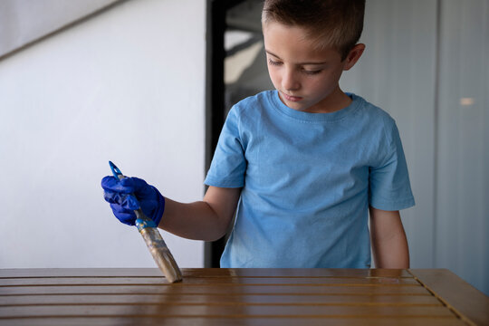 Focused Child Applying Wood Stain