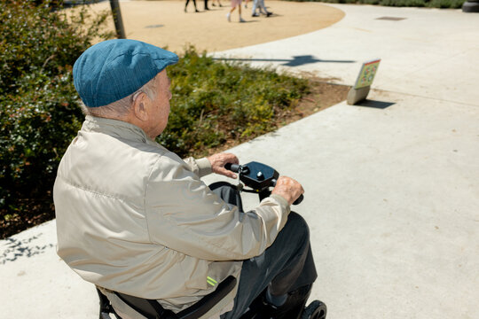 Elderly Man Riding Electric Scooter outdoors in park